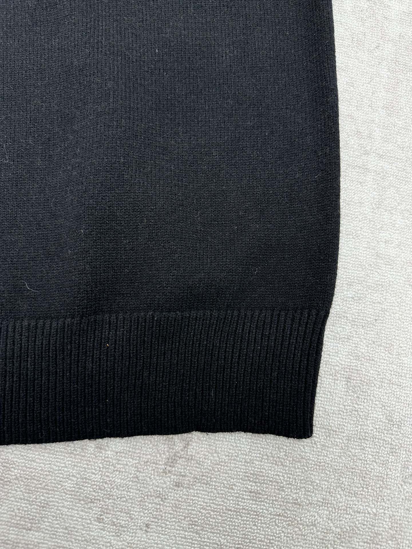 Black sweater hem with ribbed knit edge.