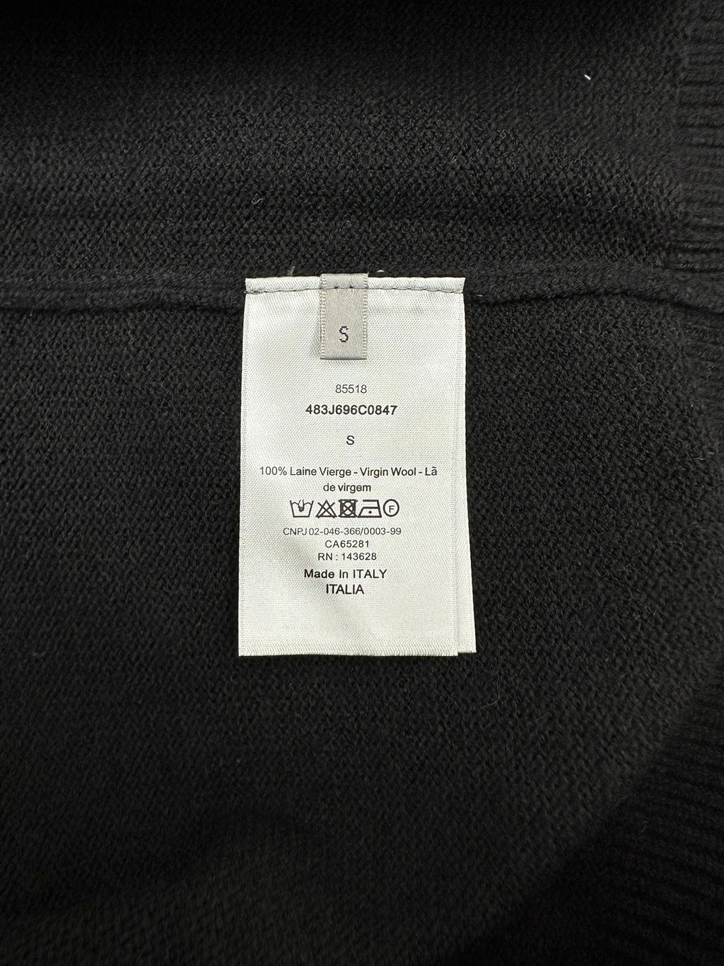 Black sweater inner size and care label, with wool content details.