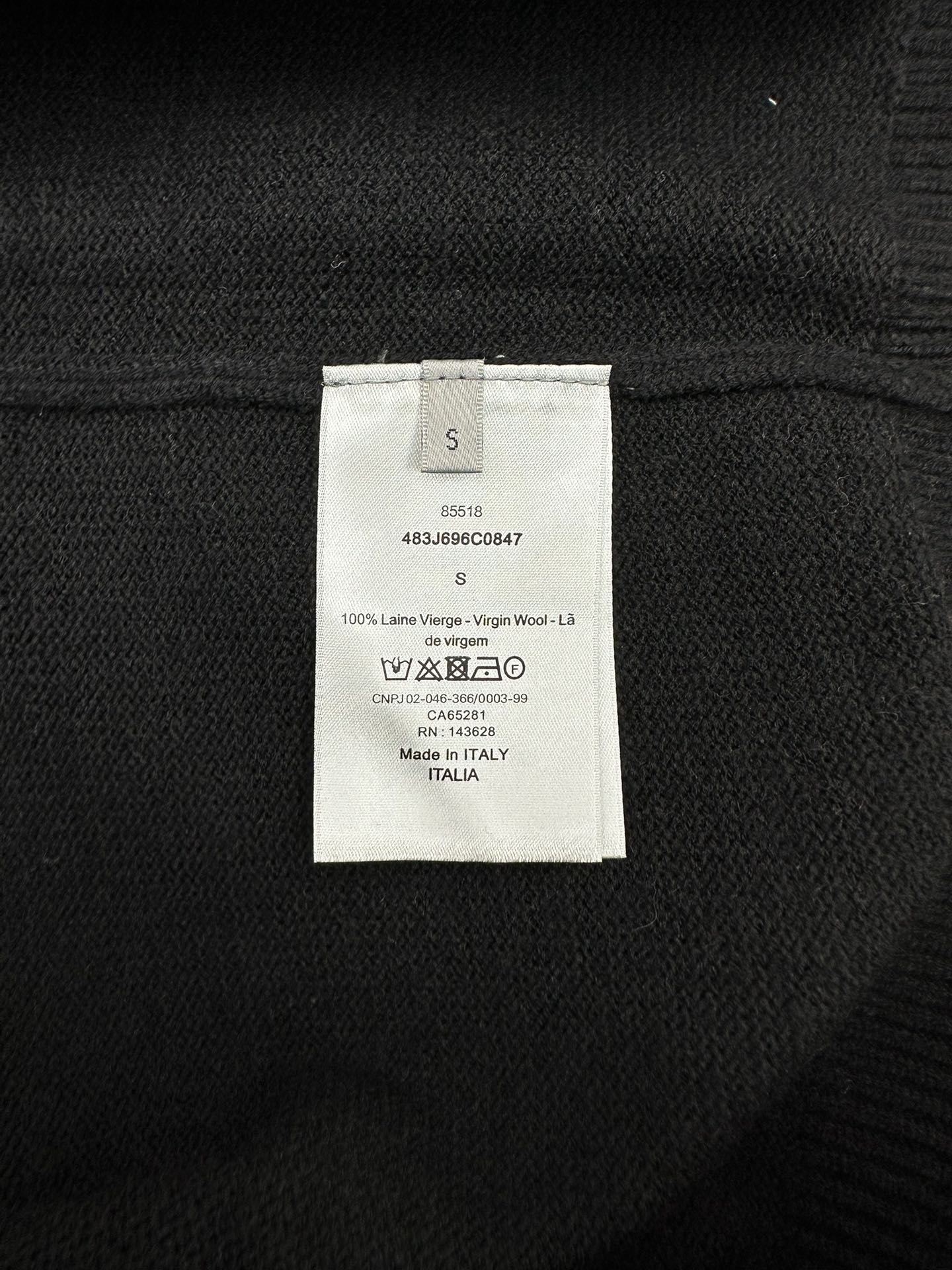 Black sweater inner size and care label, with wool content details.