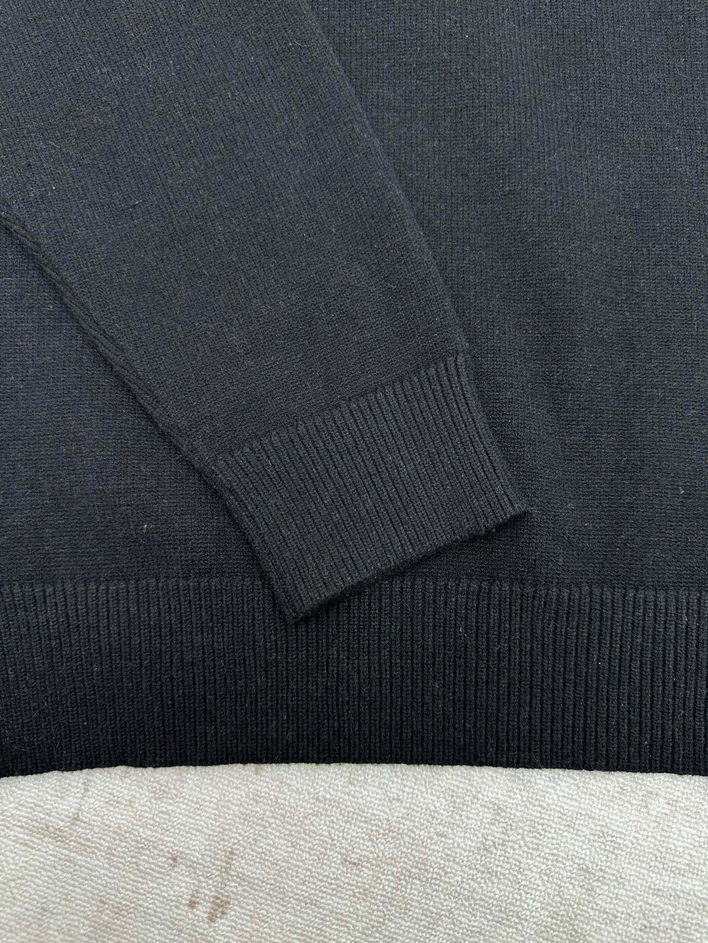 Black sweater sleeve with ribbed cuff and shoulder seam detail.