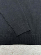 Black sweater sleeve with ribbed cuff and shoulder seam detail.