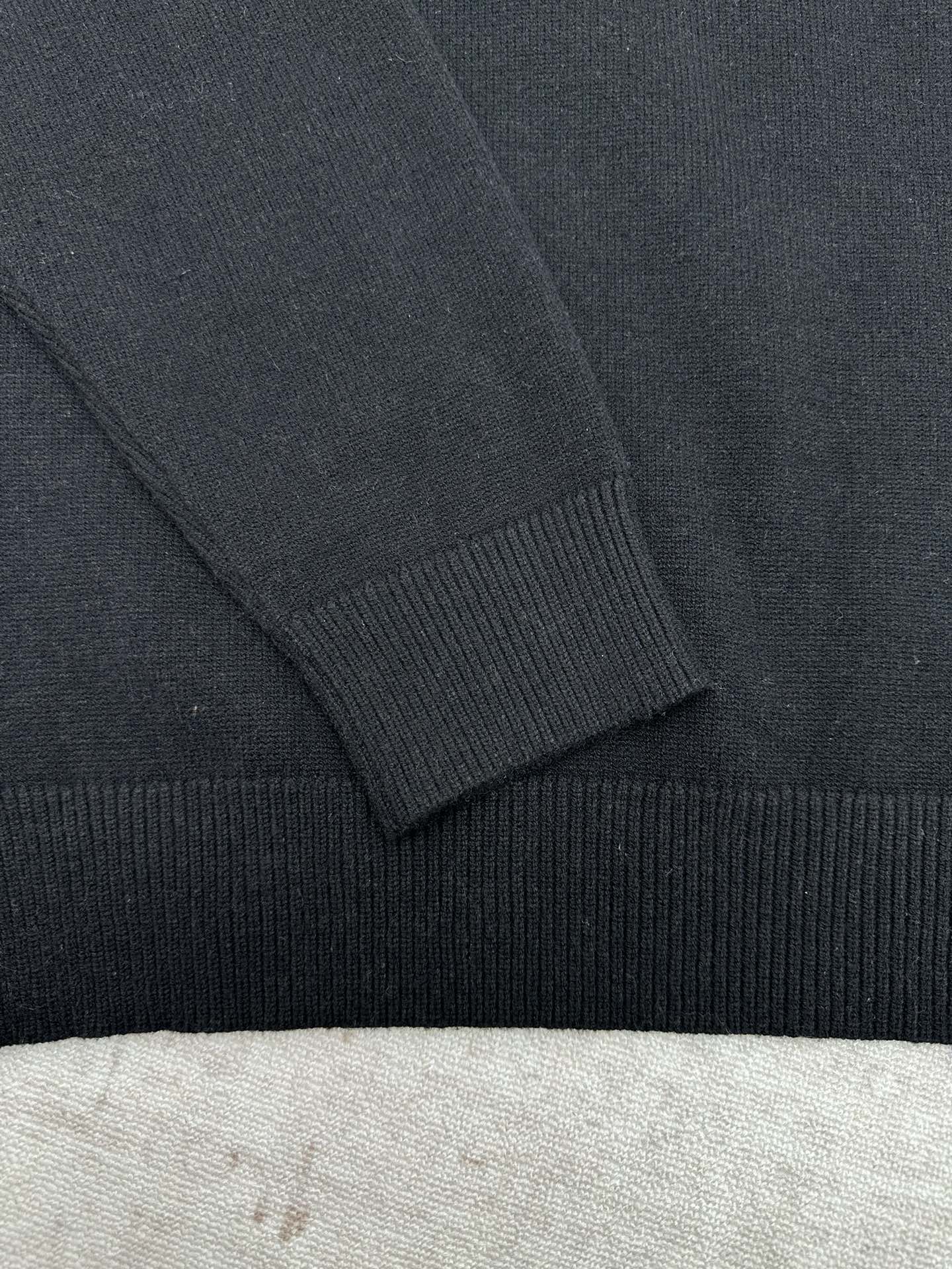 Black sweater sleeve with ribbed cuff and shoulder seam detail.