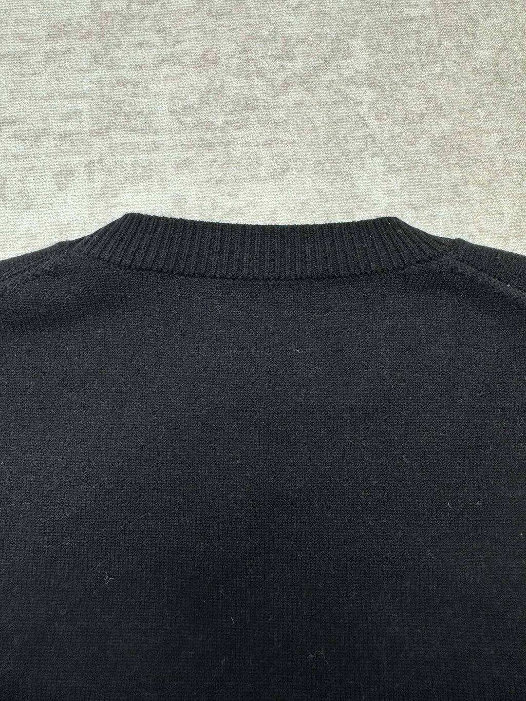 Black sweater back with ribbed crewneck collar detail.
