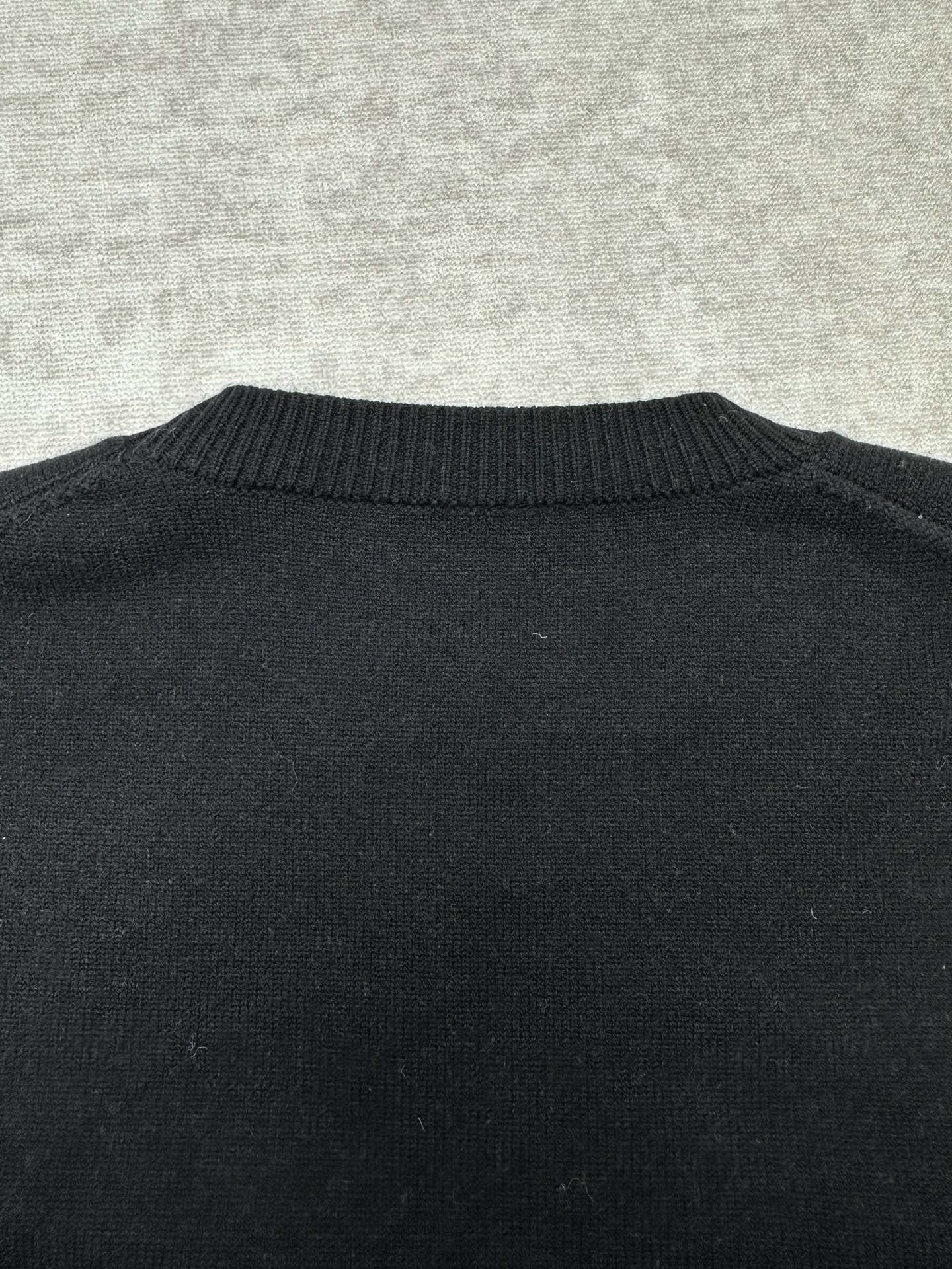 Black sweater back with ribbed crewneck collar detail.