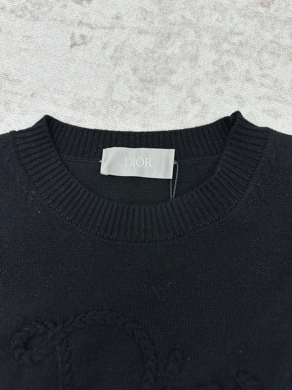 Black crewneck sweater neckline with ribbed trim and a brand neck label.