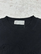 Black crewneck sweater neckline with ribbed trim and a brand neck label.