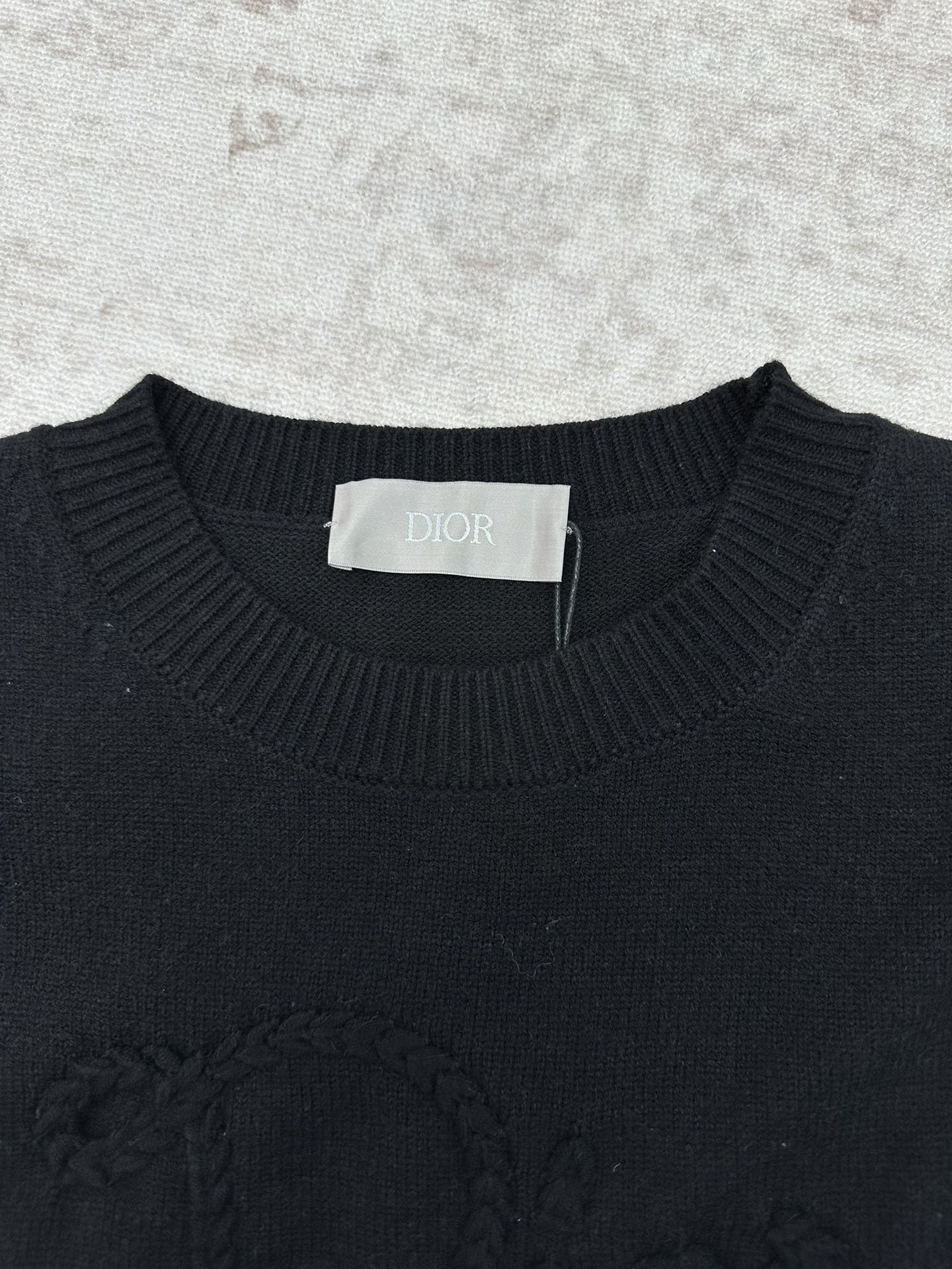 Black crewneck sweater neckline with ribbed trim and a brand neck label.