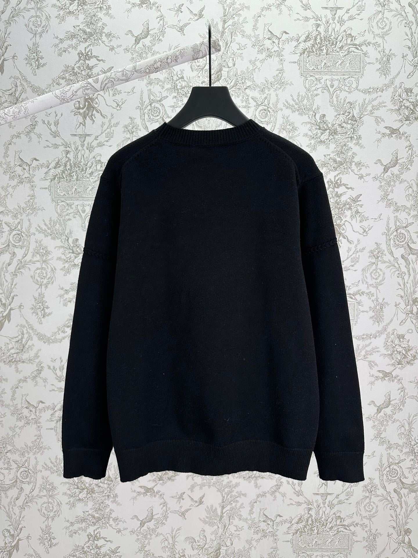 Black crewneck knit sweater, long sleeves, back view with ribbed hem and cuffs.
