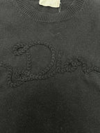 Black knit sweater with embroidered swirl logo detail on the chest.