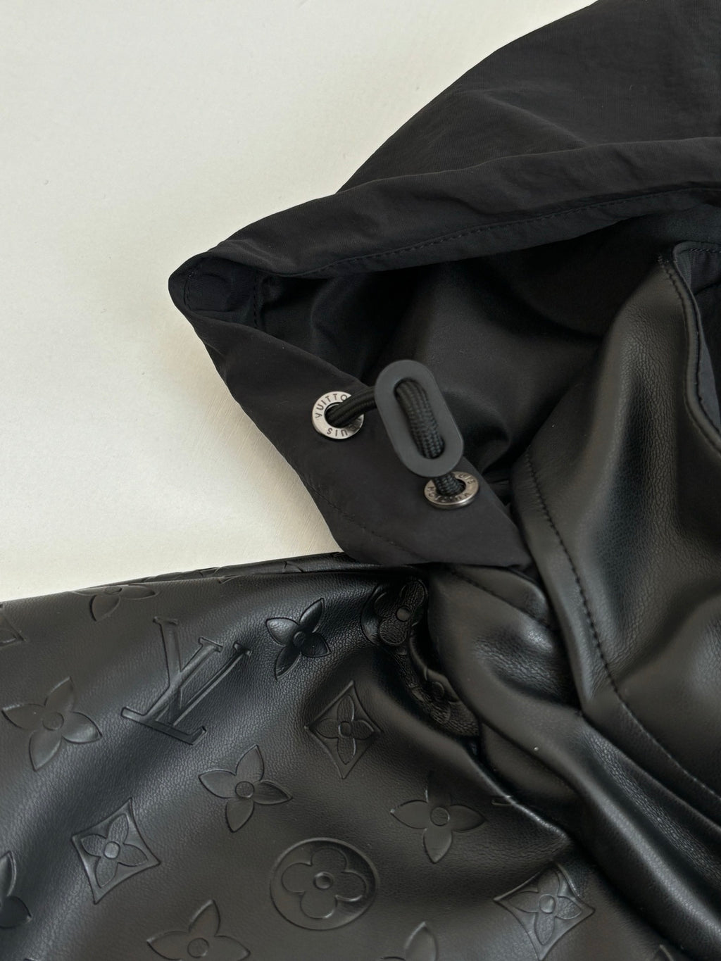 Black hood with drawstring cord and metal ring hardware, jacket detail.
