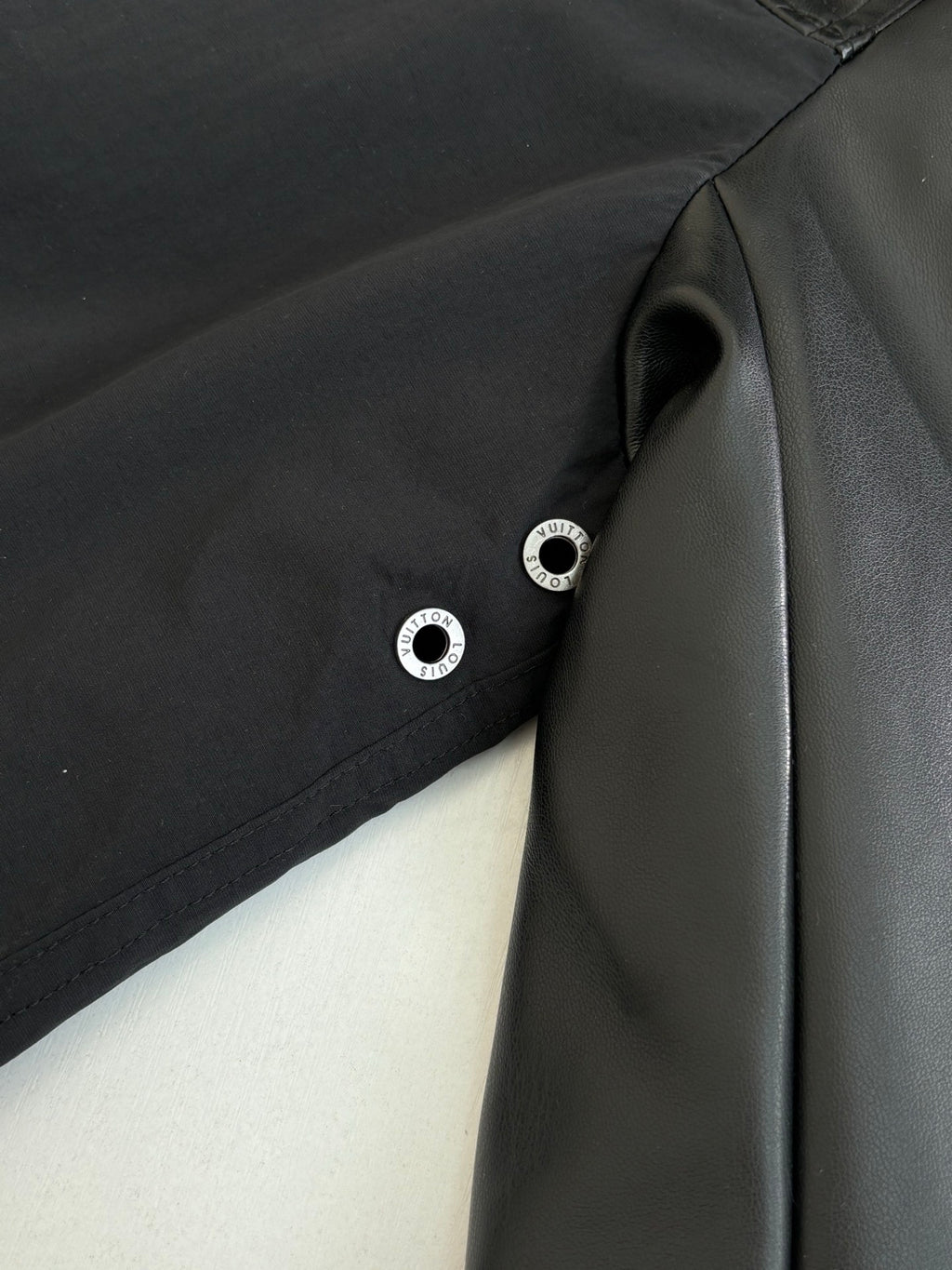 Black jacket with snap buttons and smooth panel detail near the zipper.