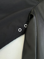 Black jacket with snap buttons and smooth panel detail near the zipper.