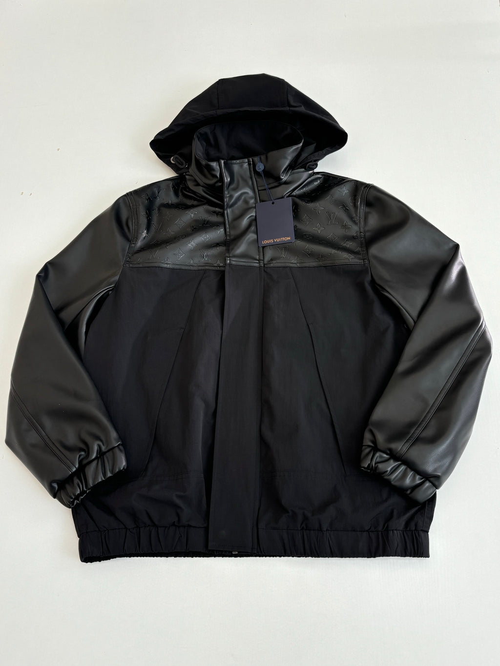 Black hooded jacket with high collar and zip front, elastic cuffs and hem.