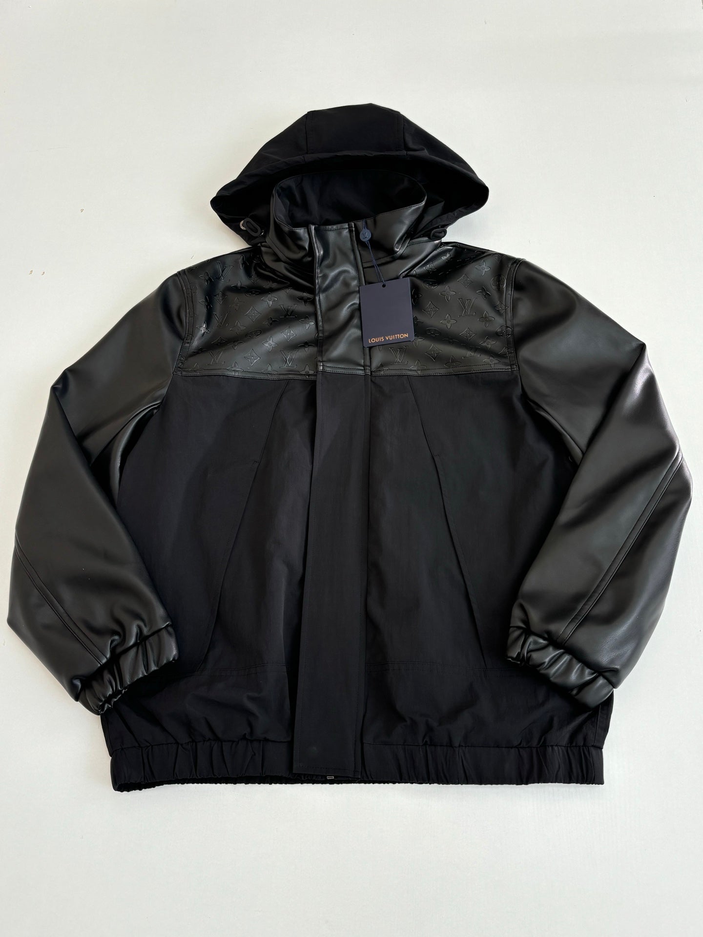 Black hooded jacket with high collar and zip front, elastic cuffs and hem.