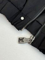 Black jacket cuff detail with round snap button and metal zipper hardware.