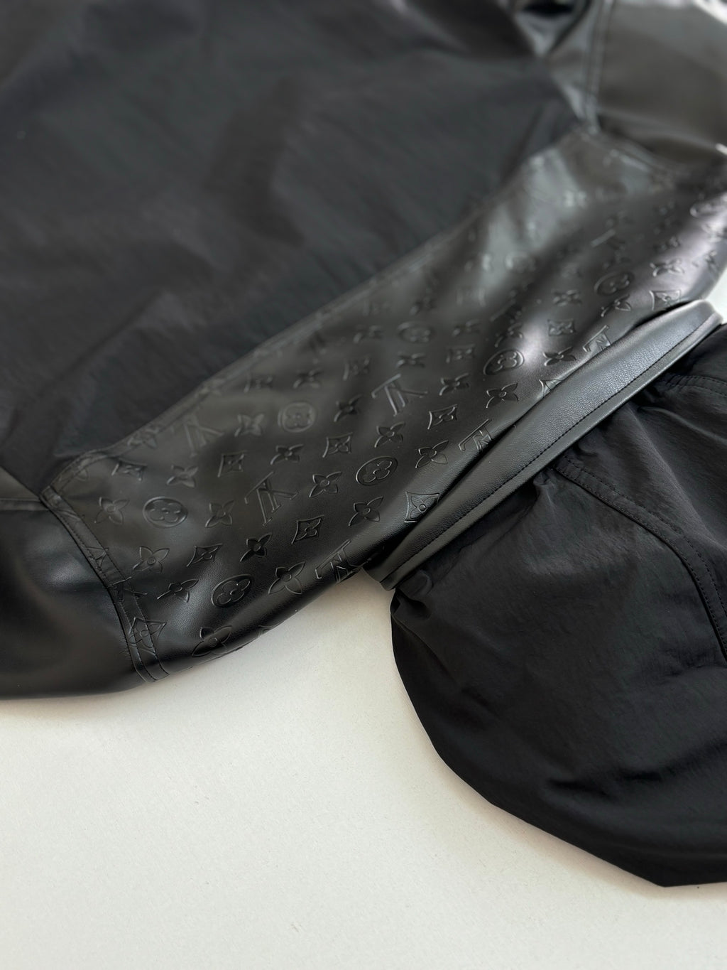 Dark long sleeve jacket, close view of embossed logo sleeve detail