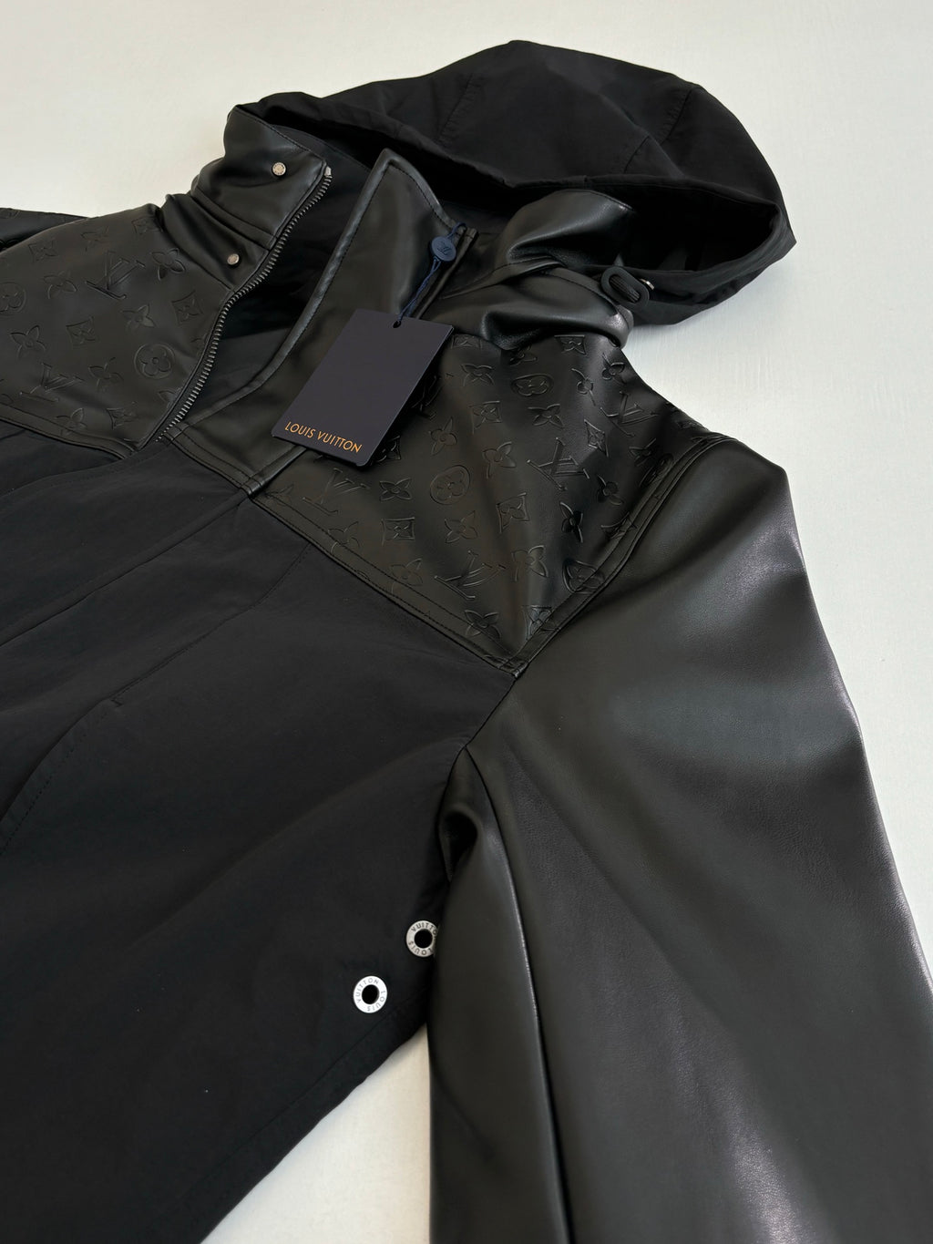 Black hooded jacket with front zipper and hood detail, with inner tag visible.