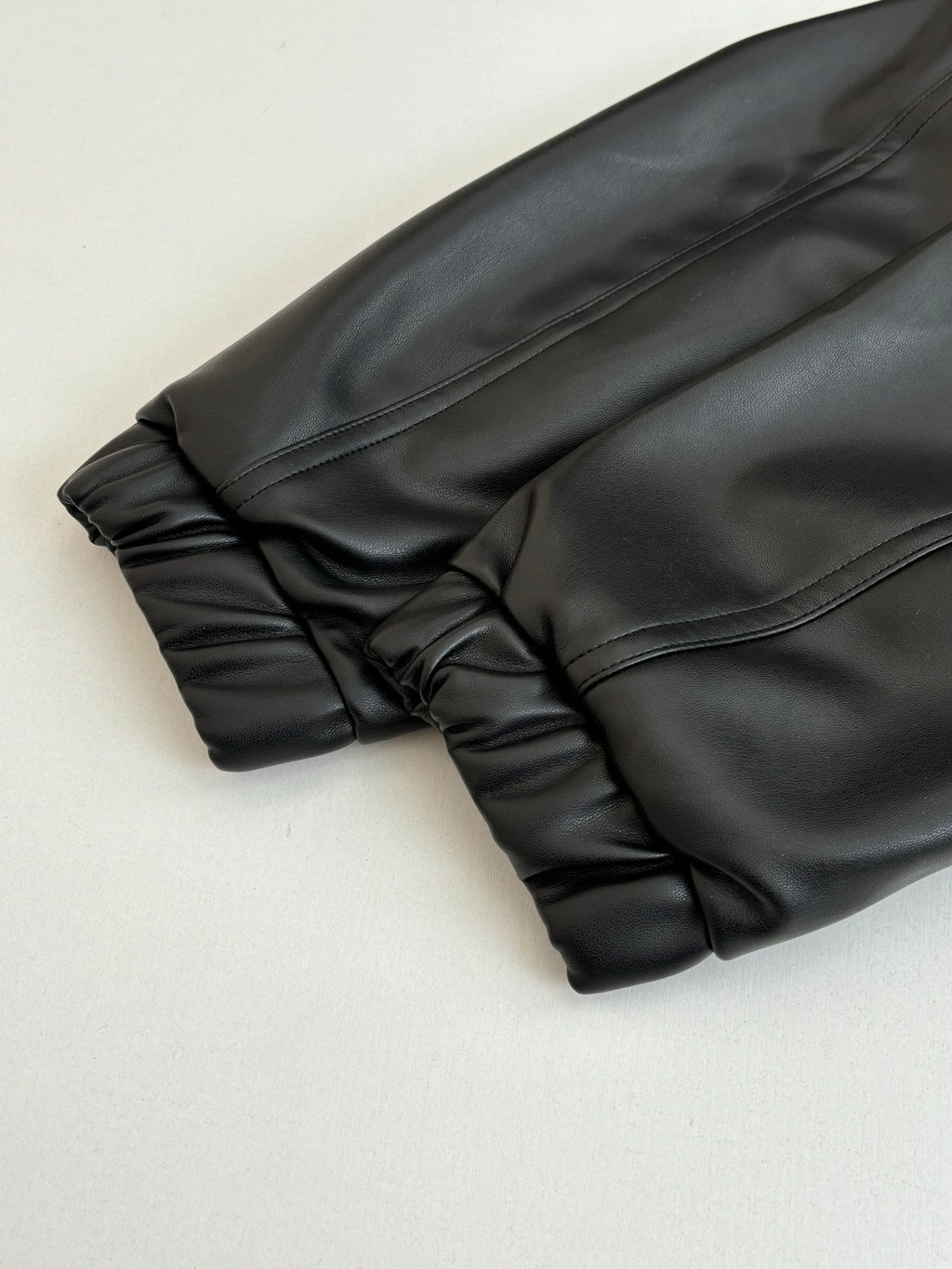 Dark long sleeve jacket, cuff and gathered hem close-up