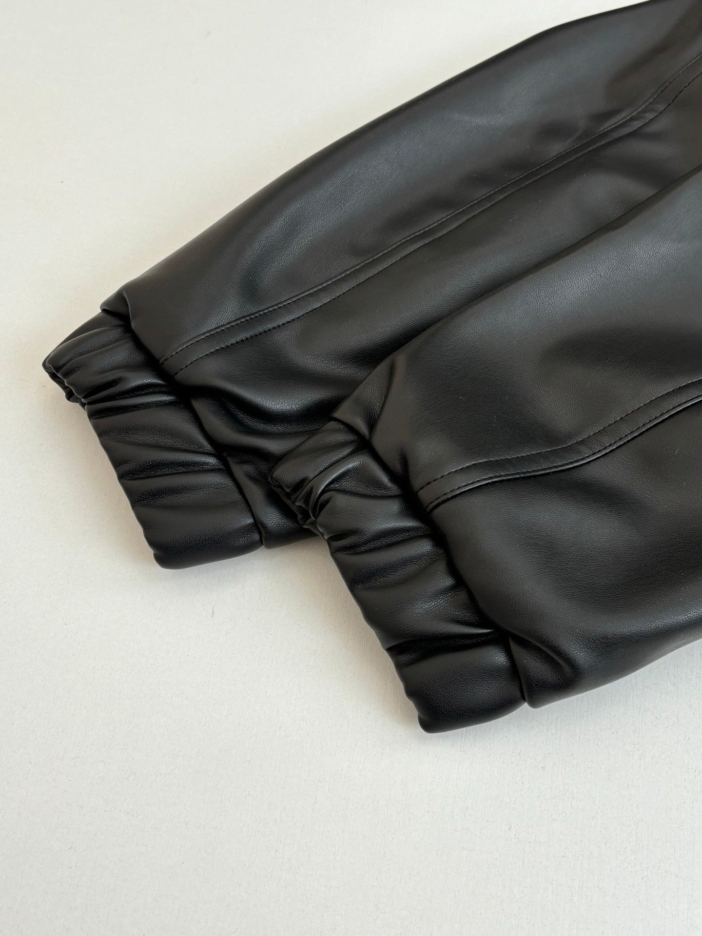 Dark long sleeve jacket, cuff and gathered hem close-up