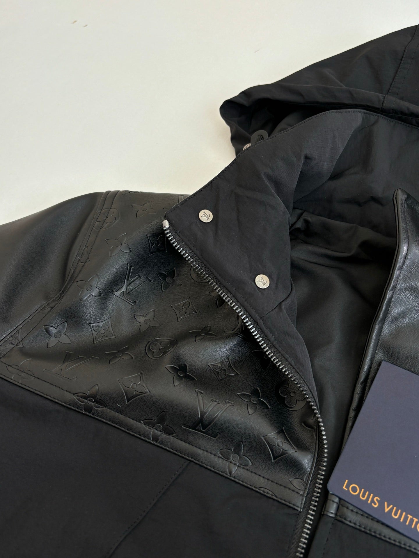 Black jacket with embossed monogram texture, side zip, and Louis Vuitton label.