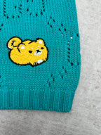 Turquoise knit sweater hem with yellow bear patch
