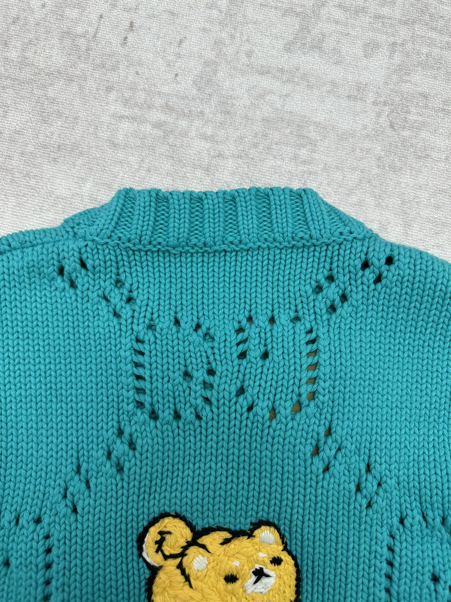 Turquoise knit sweater back with teddy bear patch and textured stitch pattern