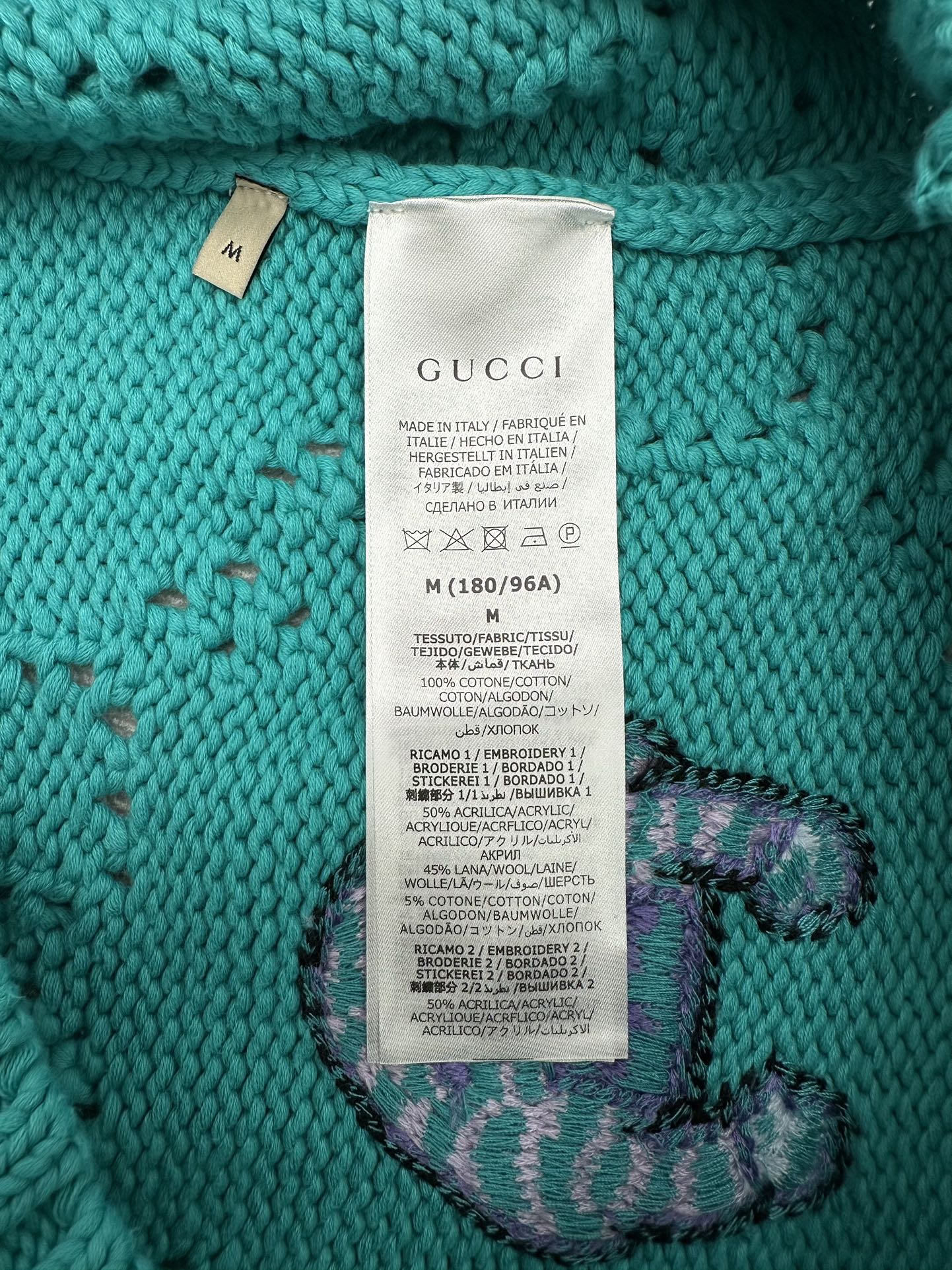 Turquoise sweater care label with Gucci branding and size M