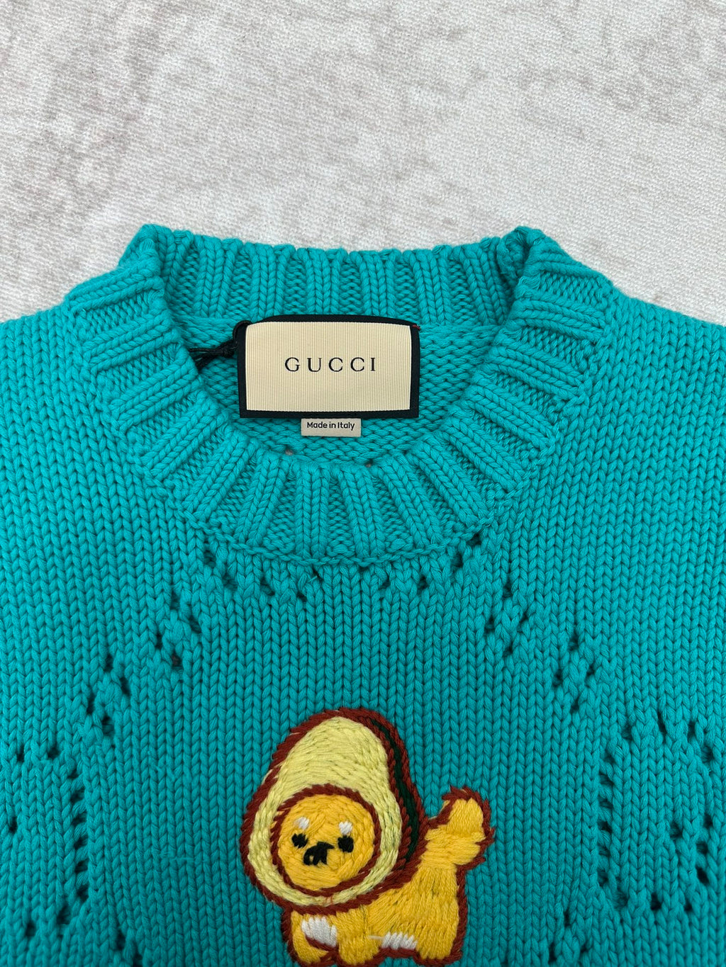 Turquoise crewneck sweater with ribbed collar and Gucci label at neckline