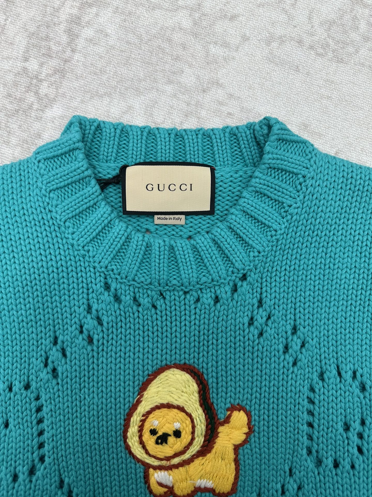 Turquoise crewneck sweater with ribbed collar and Gucci label at neckline