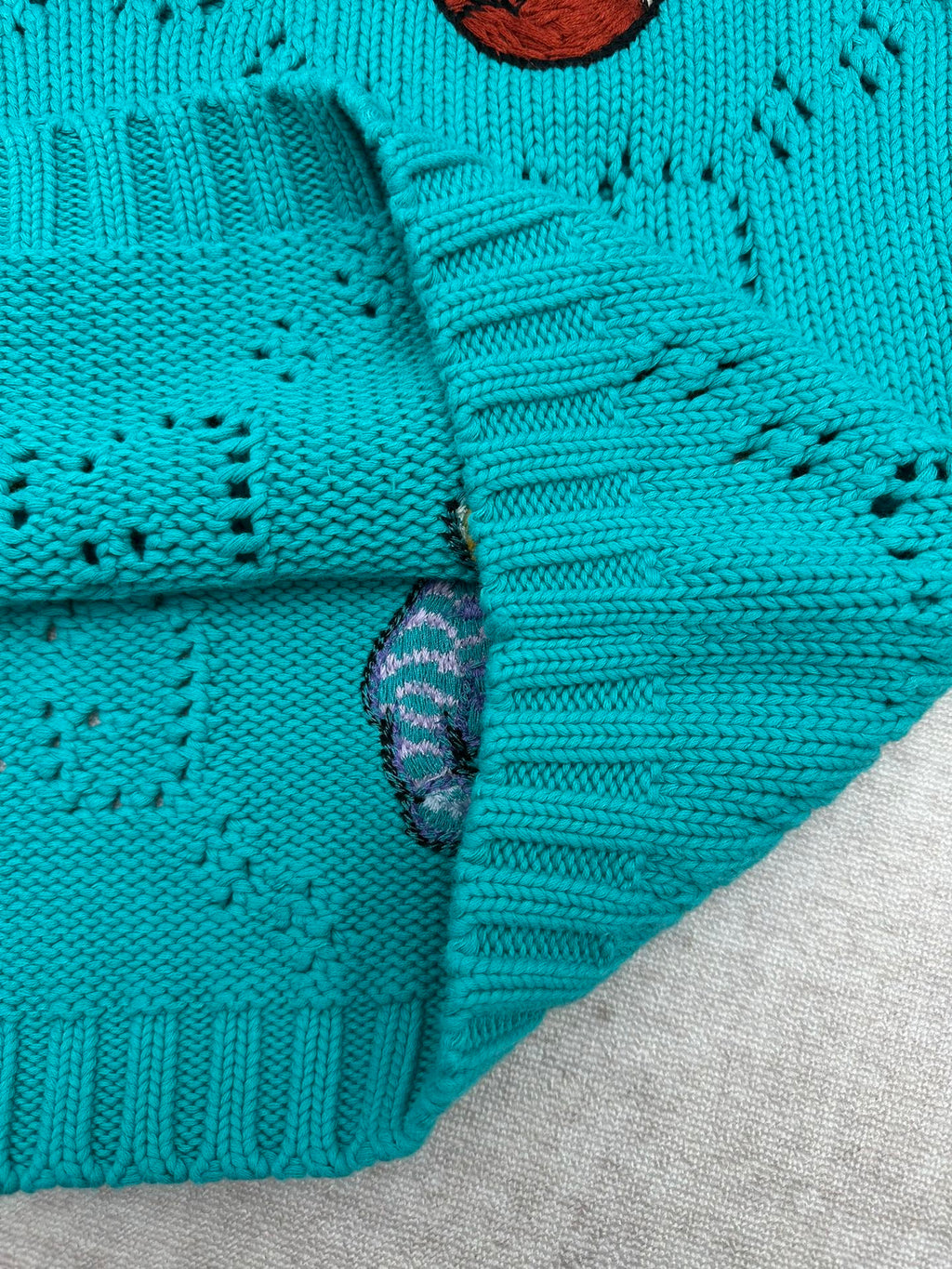 Turquoise knit sweater sleeve cuff with ribbed texture detail