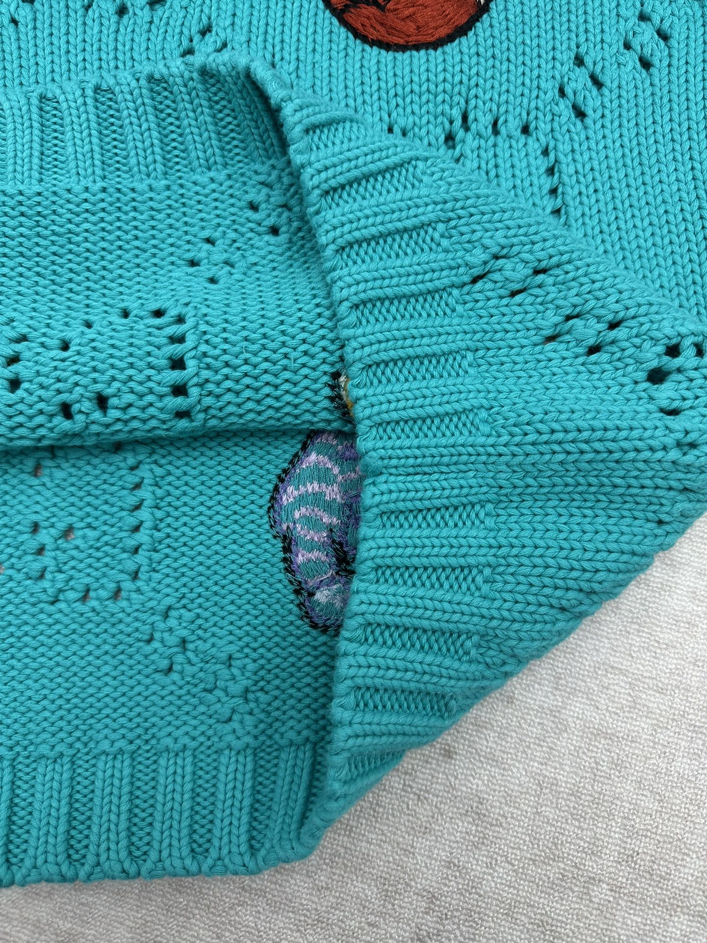 Turquoise knit sweater sleeve cuff with ribbed texture detail