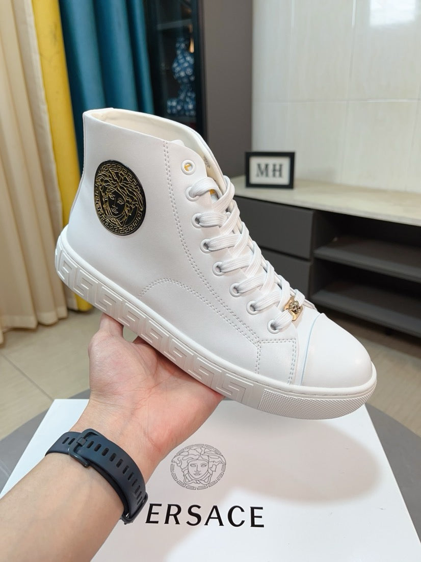 White lace-up high-top sneaker held in hand, with logo patch and gold accents.
