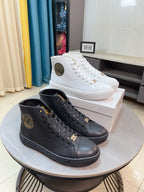 Pair of lace-up high-top sneakers, black and dark tone with logo patch.