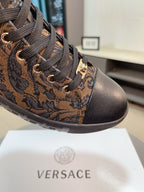 High-top sneaker close-up: brown paisley jacquard upper, black laces, gold-tone eyelets.