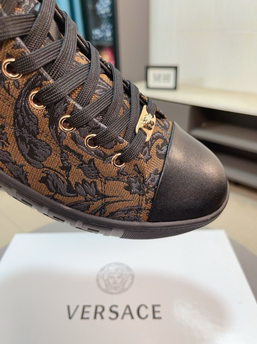 High-top sneaker close-up: brown paisley jacquard upper, black laces, gold-tone eyelets.
