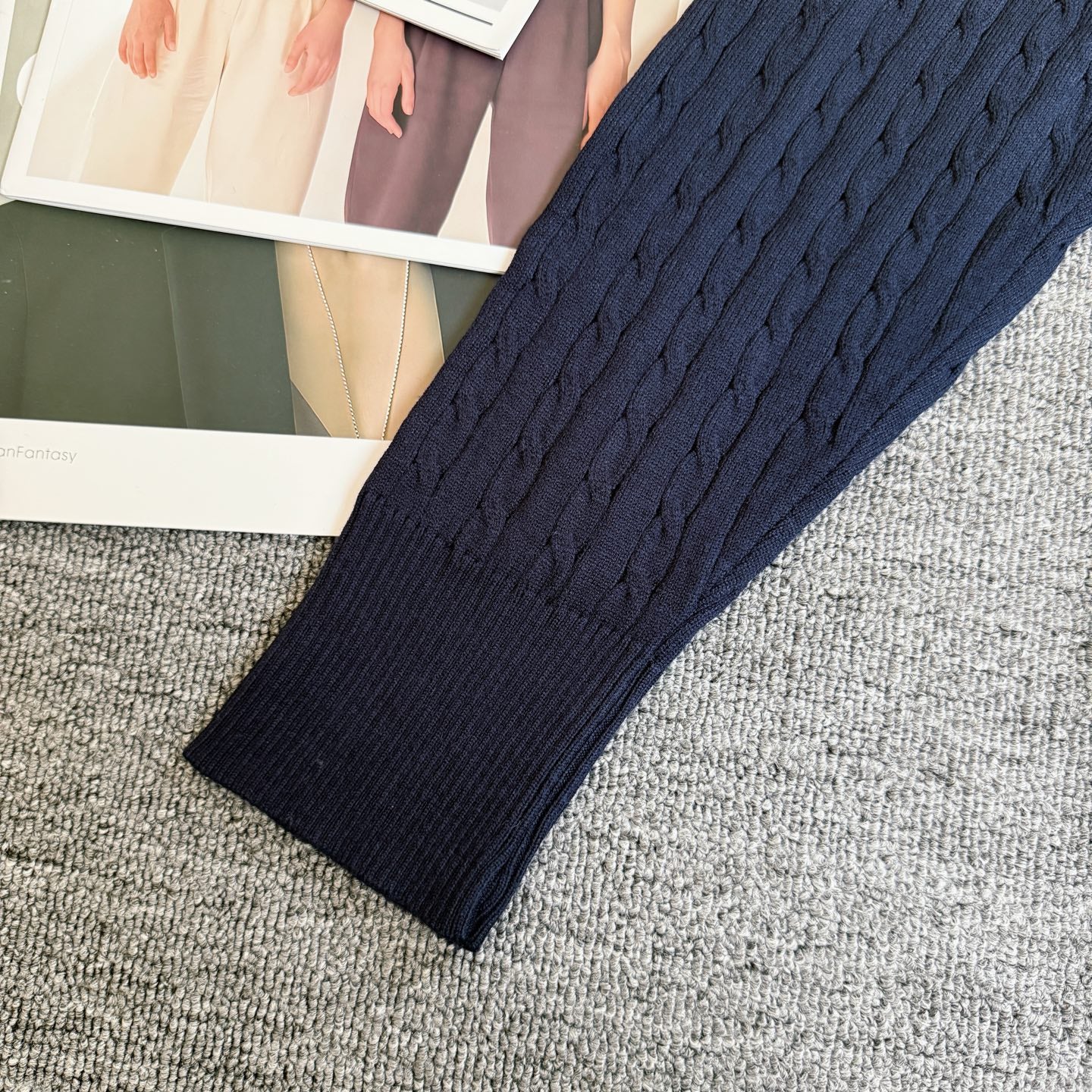 Navy cable-knit cardigan sleeve with ribbed cuff and textured knit body