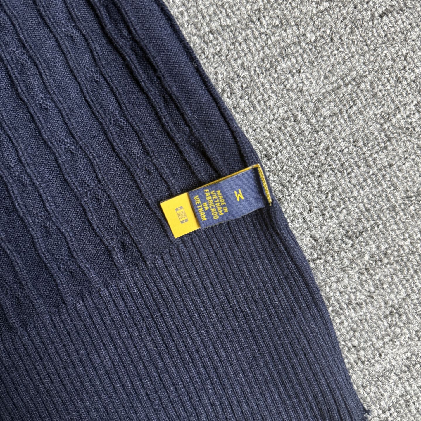 Navy knit sleeve cuff with ribbed trim and yellow size label