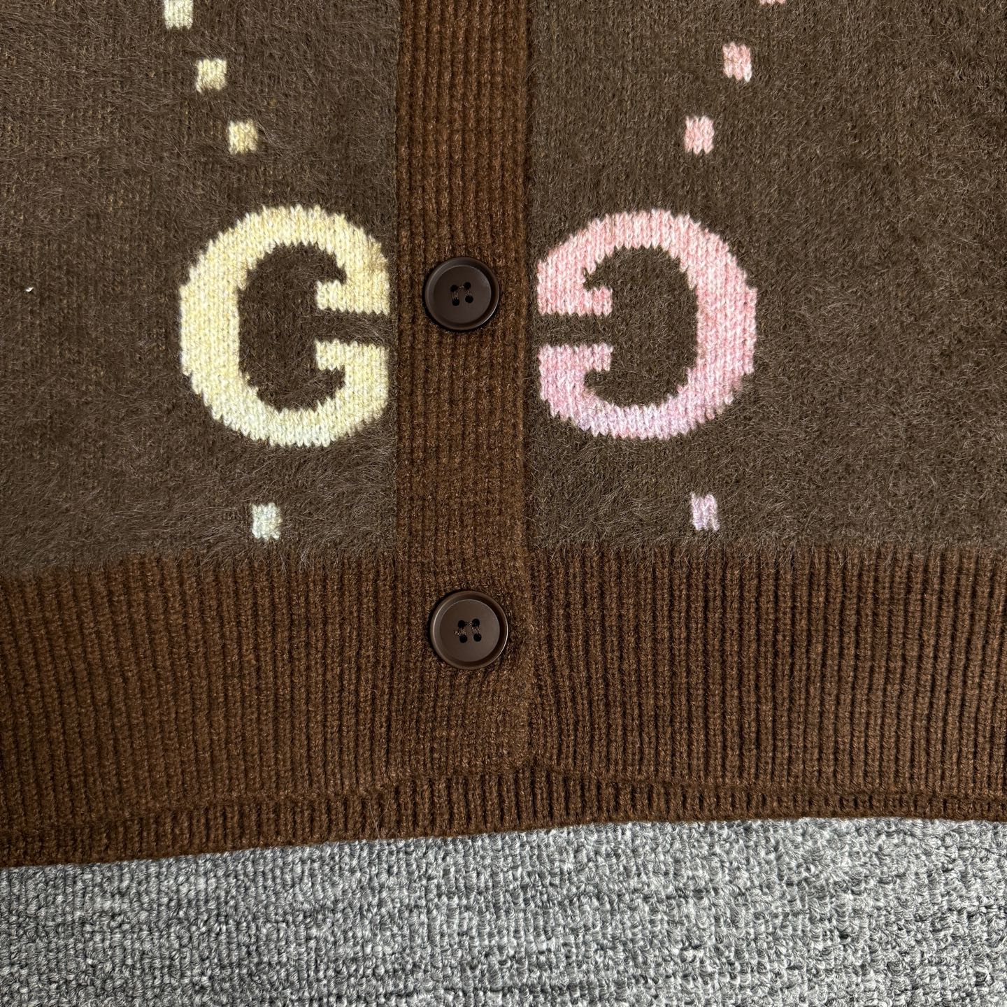 Brown Gucci logo knit cardigan button-front close-up with GG motifs and ribbed hem.