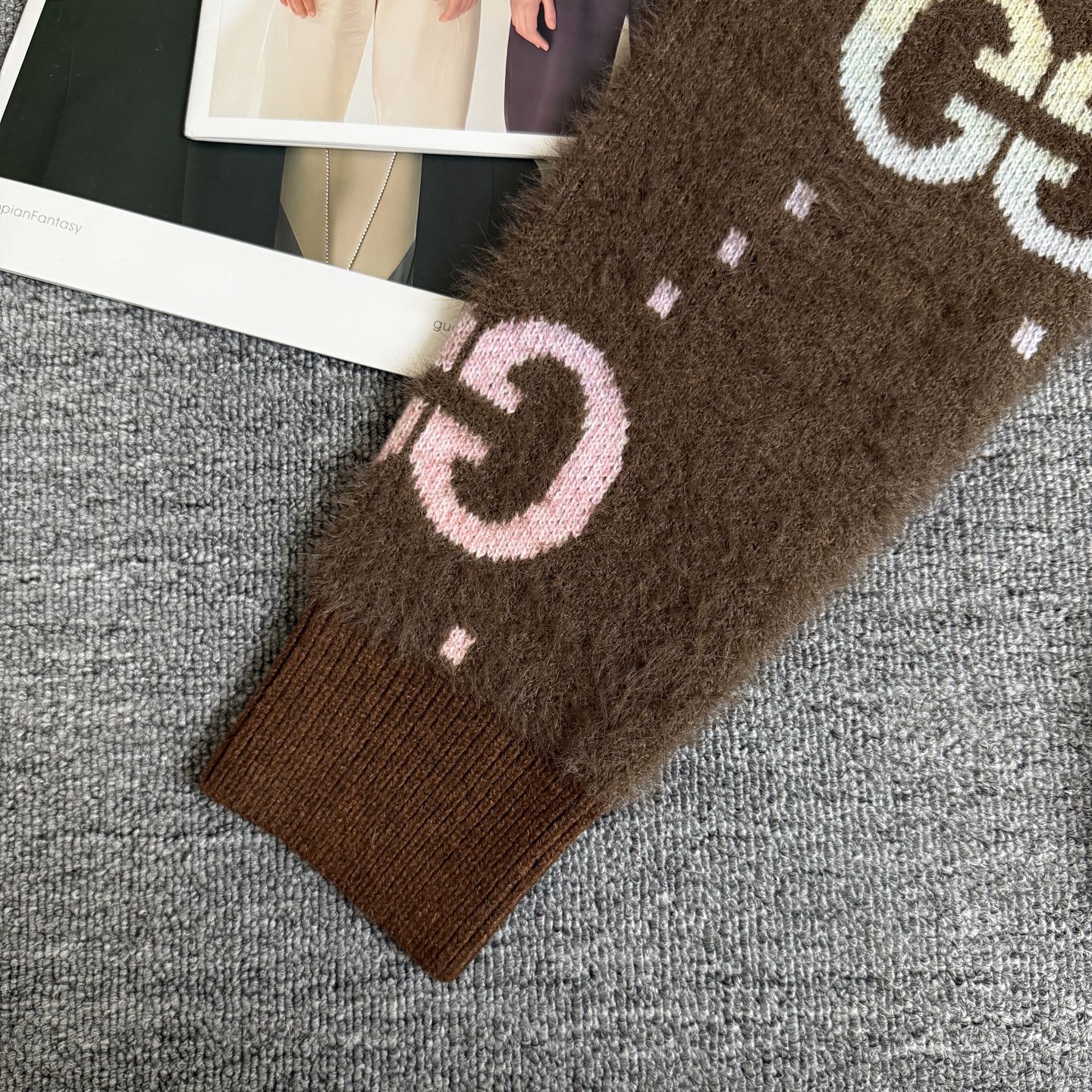 Brown Gucci logo knit cardigan sleeve cuff close-up with pink and white GG motif.