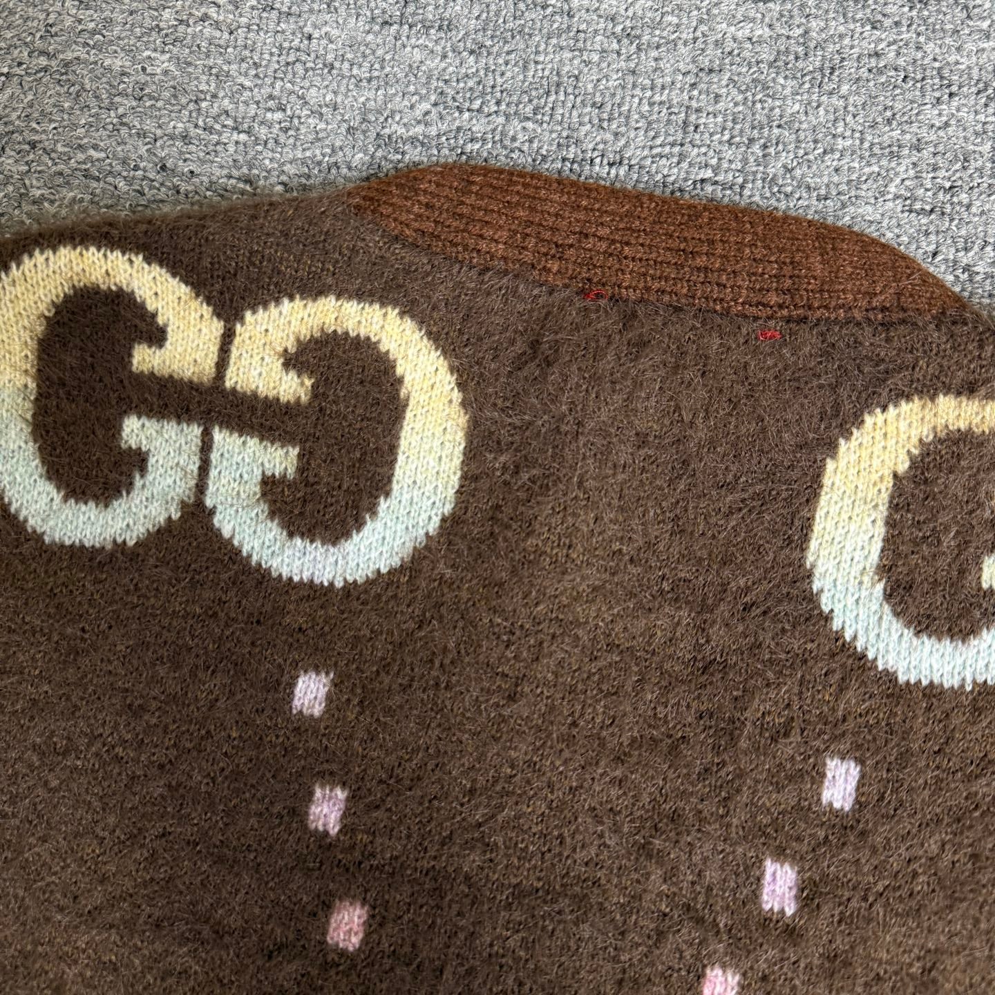 Brown Gucci logo knit cardigan upper close-up with large GG emblem and dotted pattern.
