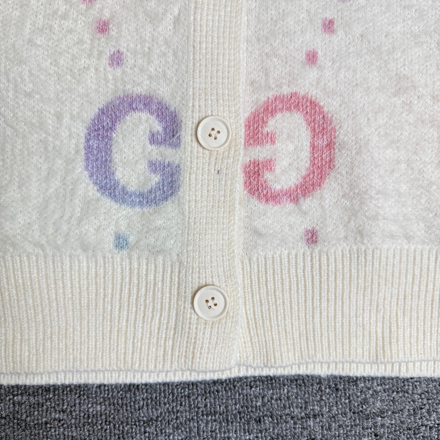 Gucci knit cardigan front detail with two buttons and colorful GG letters on off-white
