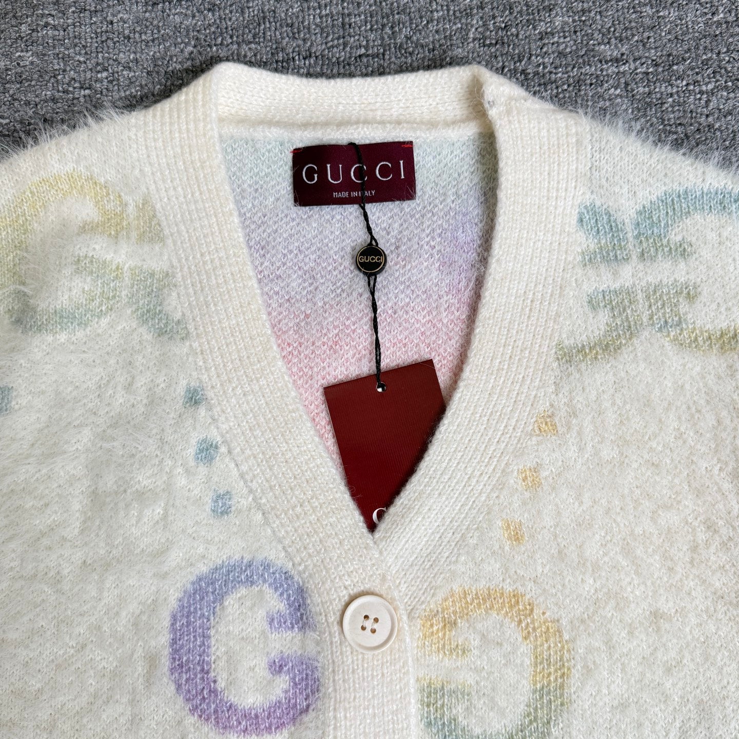 Gucci knit cardigan neckline with Gucci label and button placket on off-white fabric