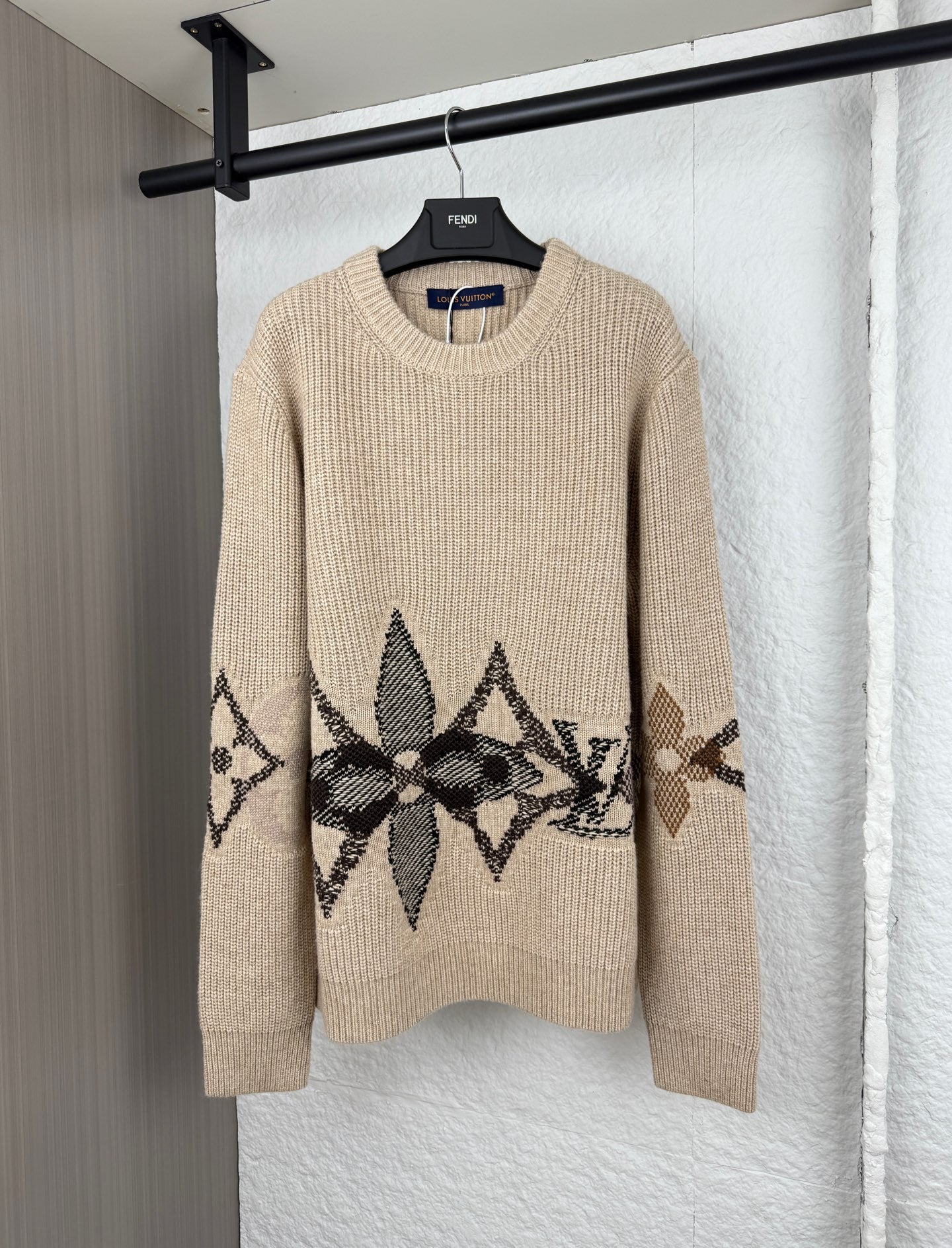 Beige knit sweater with black geometric logo graphic and long sleeves