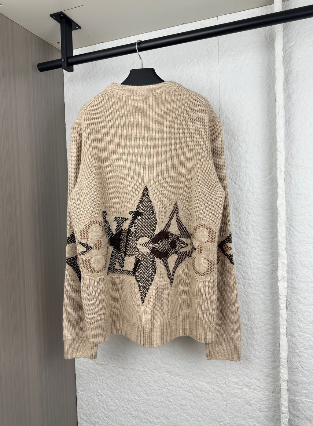 Beige knit sweater back with black geometric logo graphic and long sleeves