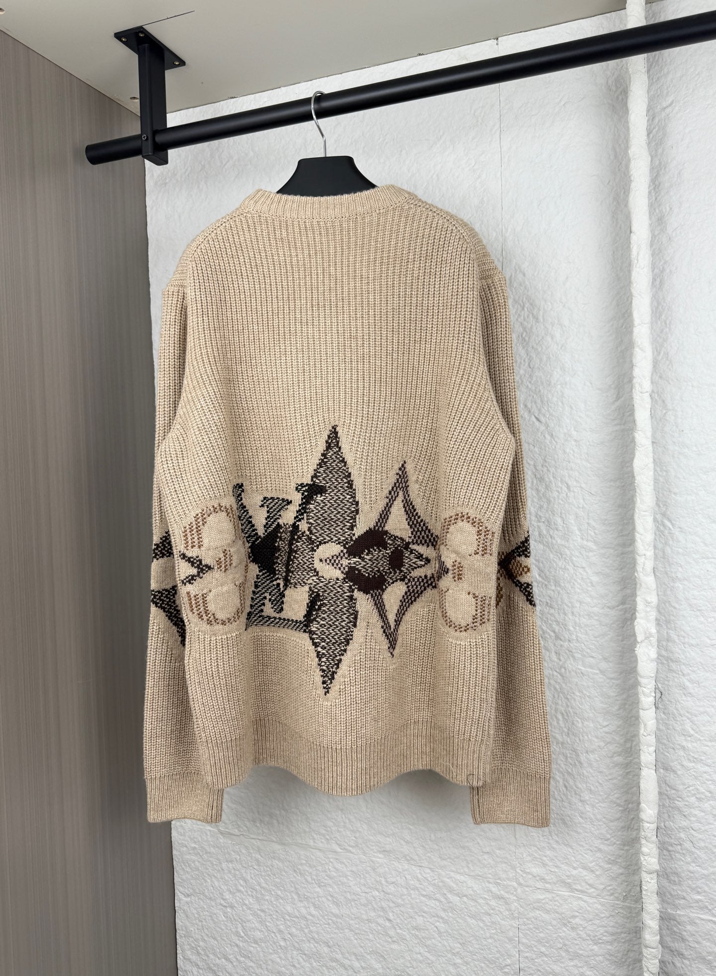 Beige knit sweater back with black geometric logo graphic and long sleeves