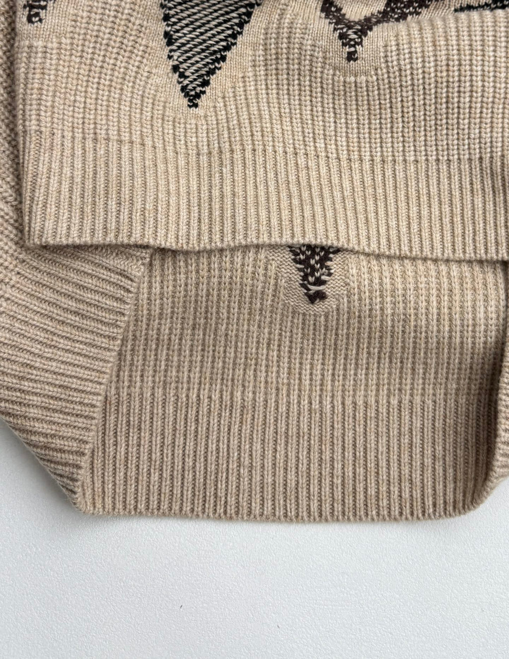 Beige knit sweater hem with black geometric intarsia design