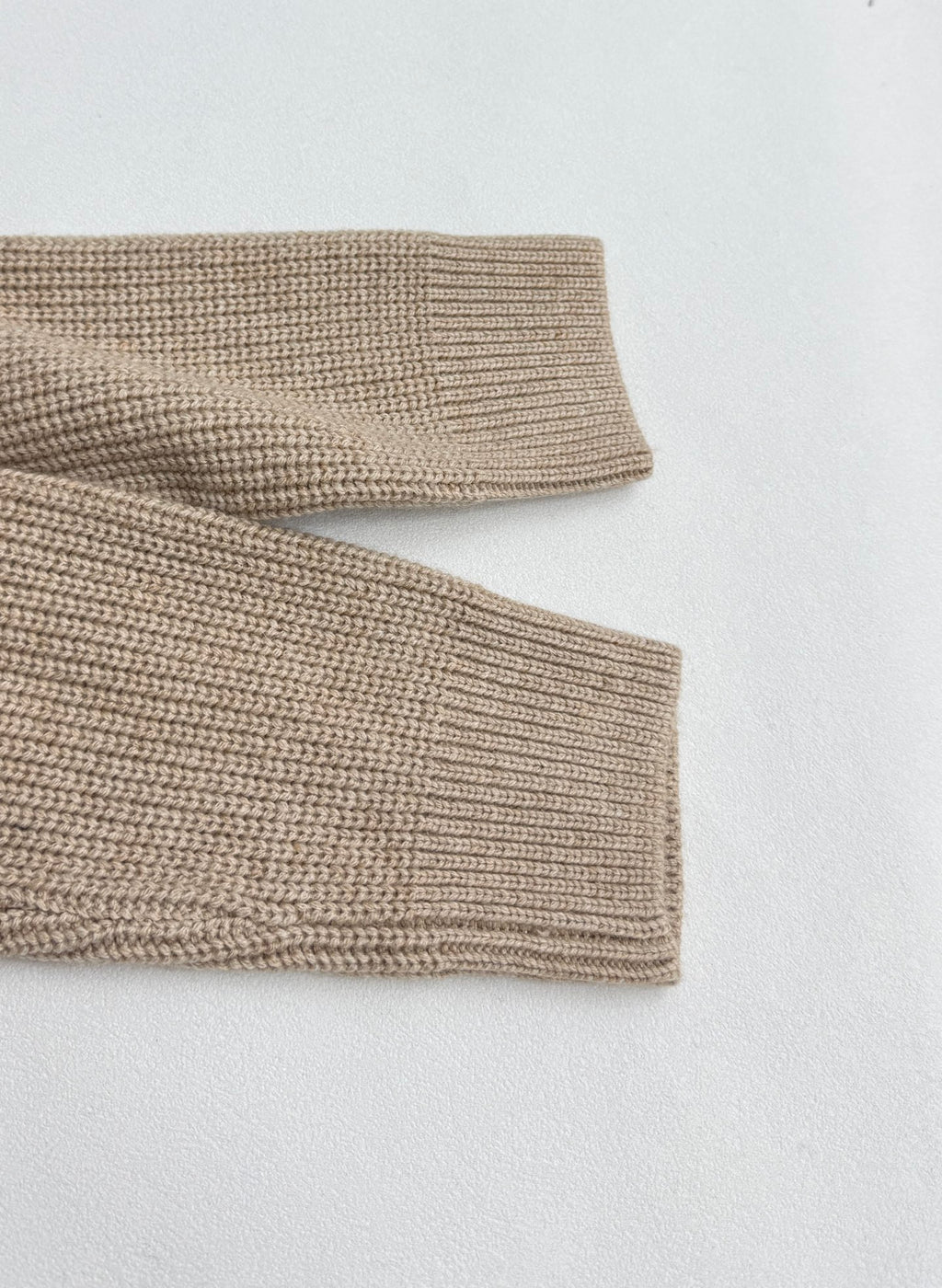 Beige knit sweater sleeve cuffs with ribbed knit hem