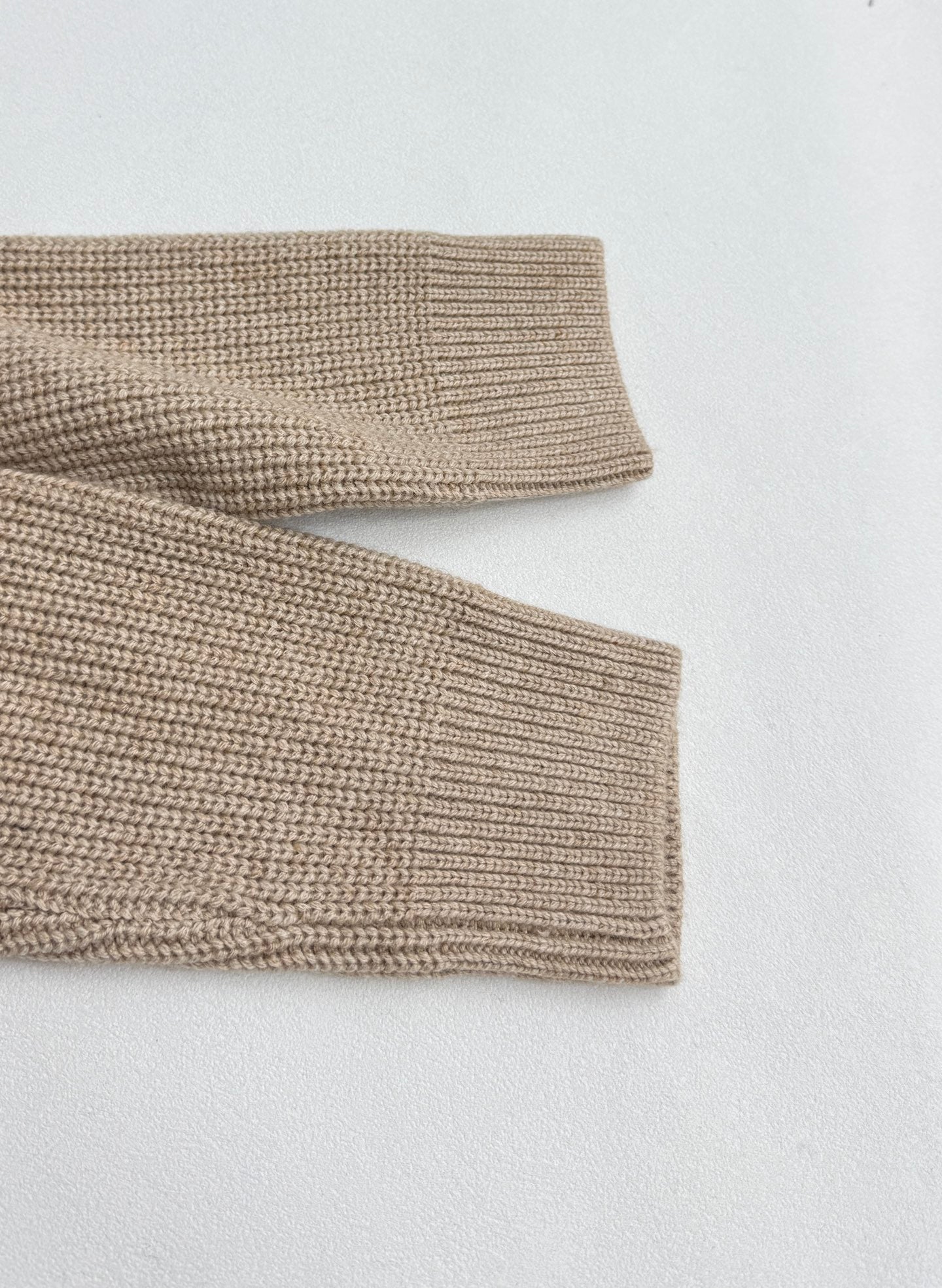 Beige knit sweater sleeve cuffs with ribbed knit hem