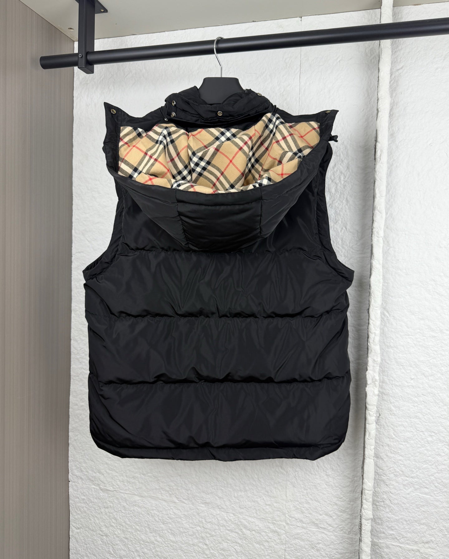 Black hooded puffer vest with plaid-lined inner hood, back view