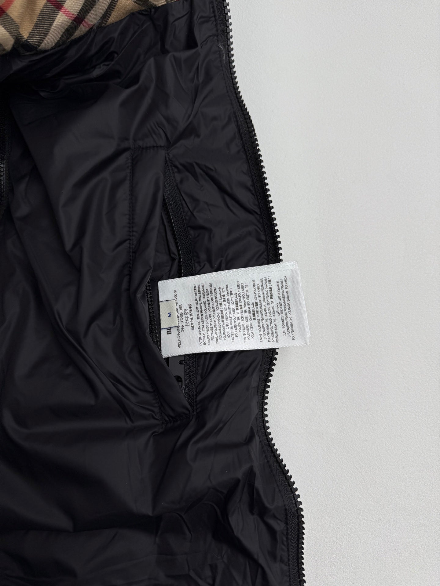 Black long puffer jacket with zip, high collar, and size label